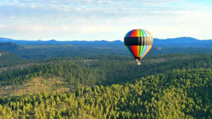 hot air balloon flies over the Black Hills of South Dakota